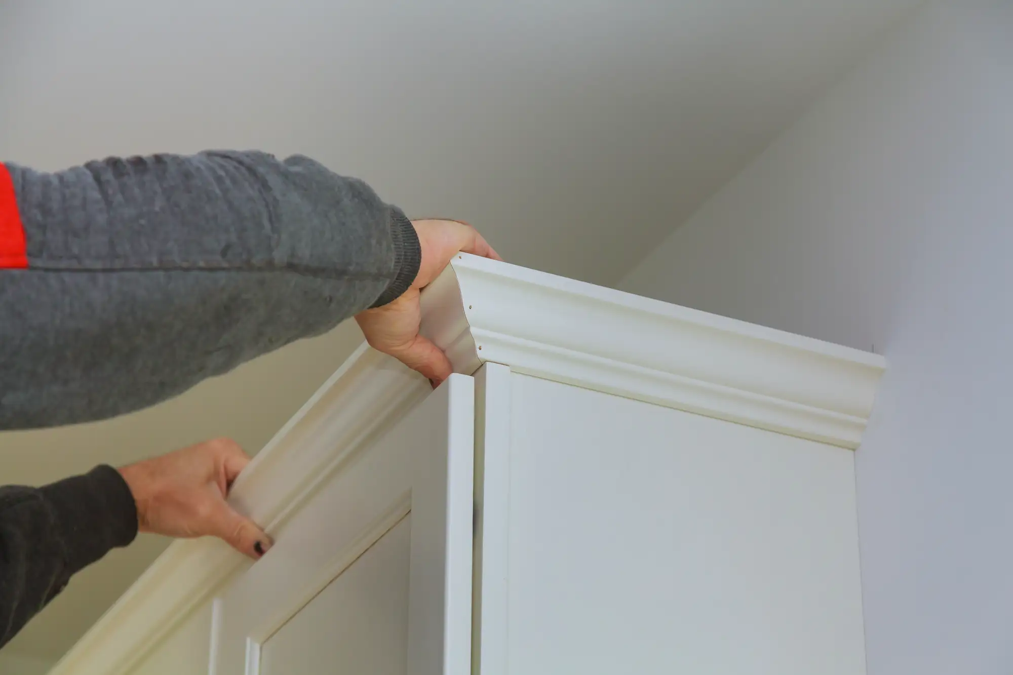 Man attaching crown moulding to kitchen cabinets